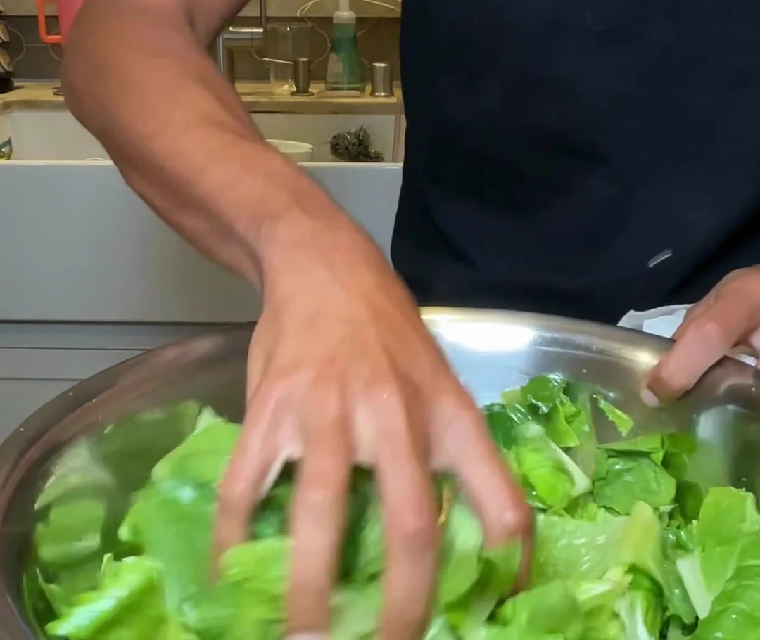 Romaine being tossed in the filmed Caesar bowl